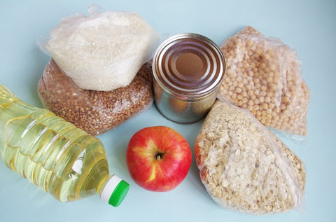 Lebensmittelvorrat mit Ölflasche, Konservendose, Apfel, Reis, Haferflocken, Buchweizen und Kichererbsen