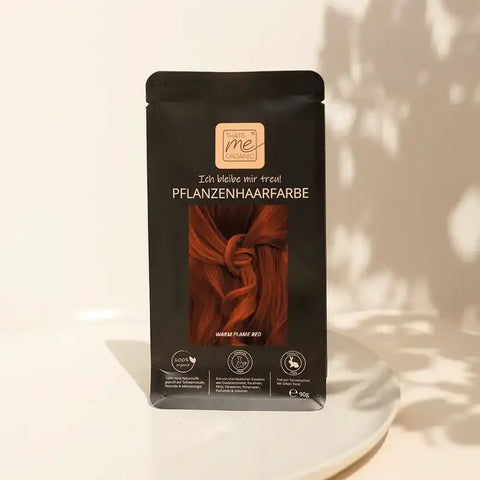 Pflanzenhaarfarbe Packung warm flame red auf weißem Teller, natürliches Licht