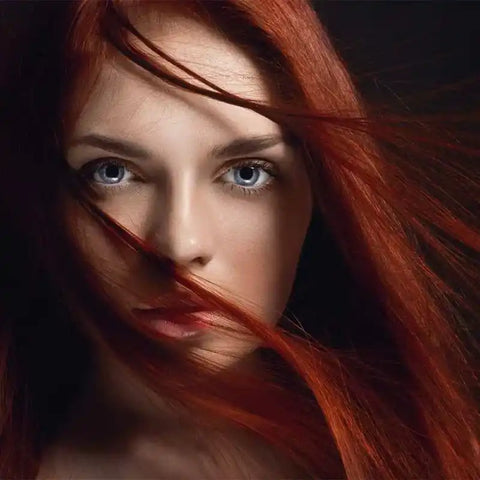 Nahaufnahme einer Frau mit leuchtend roten Haaren und blauen Augen, Haarpflege Fokus